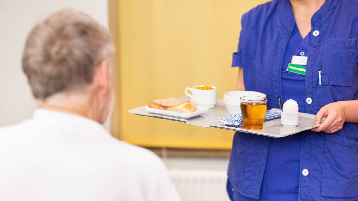Vårdpersonal levererar en frukostbricka till patient.