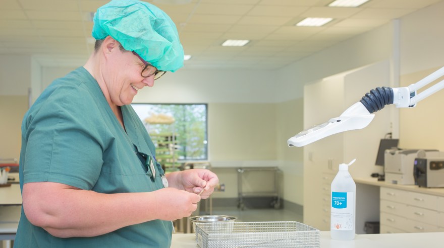 Person med arbetskläder arbetar med sterila instrument..