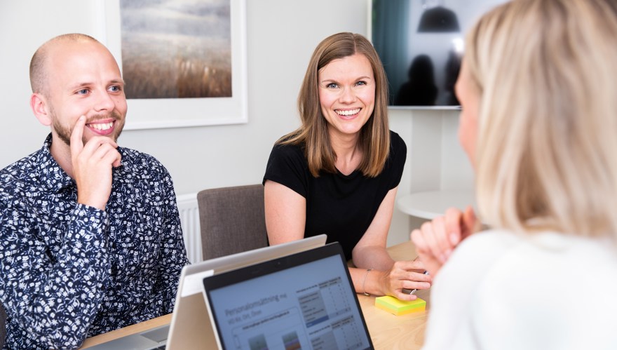 Tre personer vid ett bord i ett konferensrum med datorer framför sig på et bord.