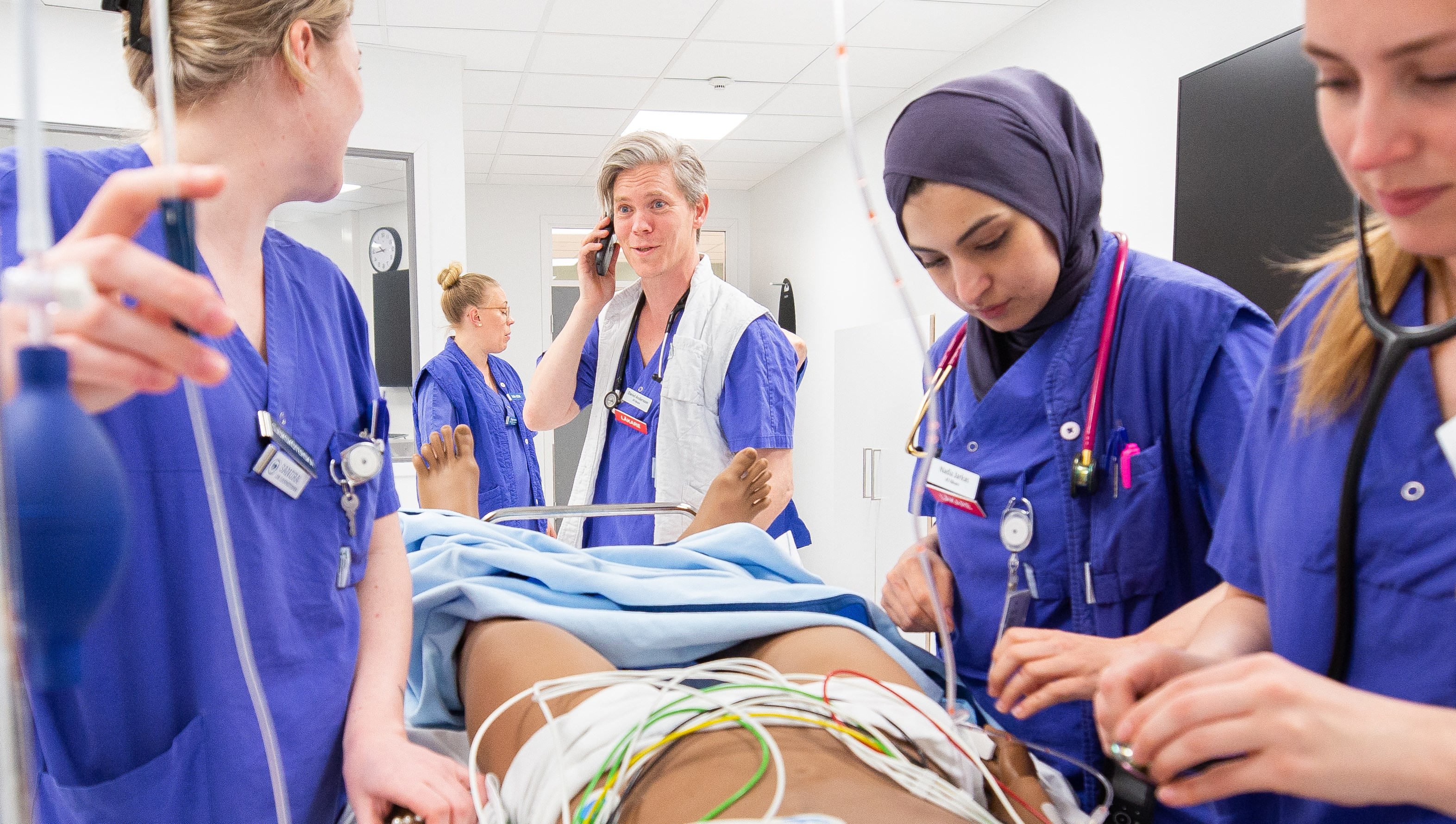 Fem personer övar på att ge vård. De tränar på en docka.