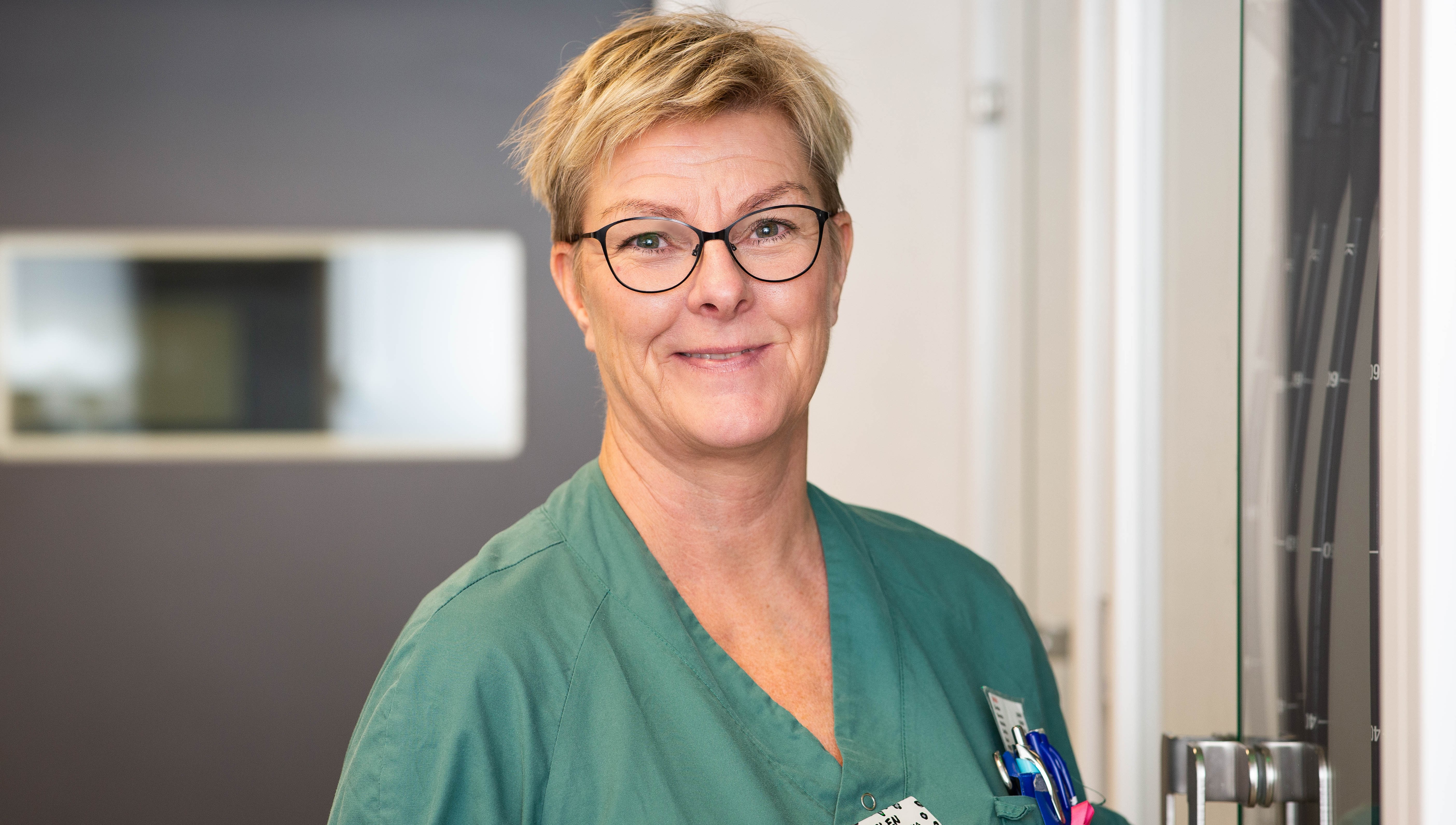 Porträtt av kvinnlig vårdpersonal i gröna arbetskläder.