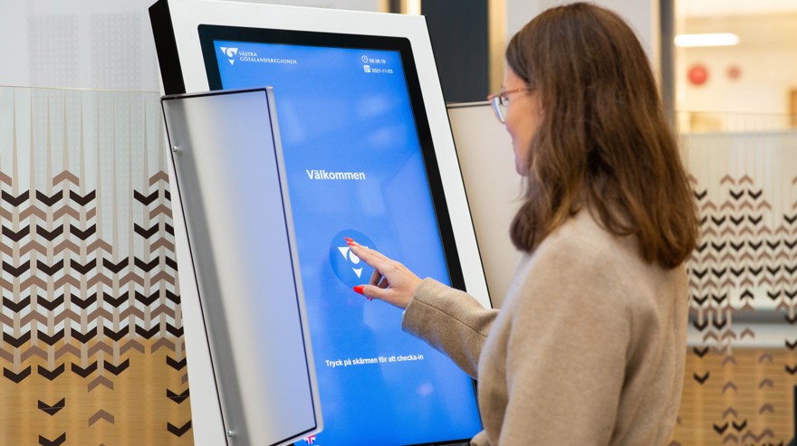 Kvinna i entrén checkar in på skärm