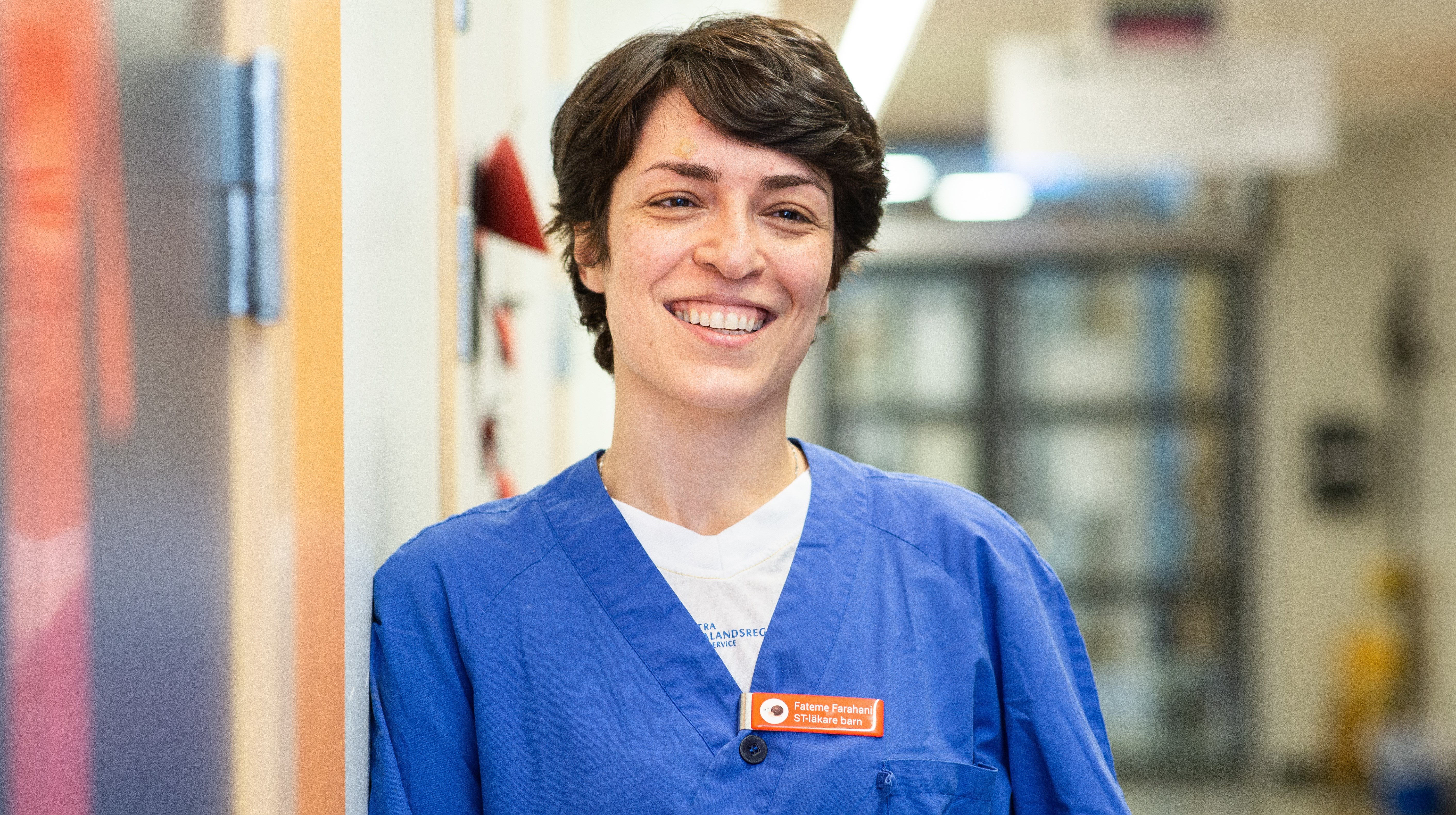 Bröstbild på kvinna i arbetskläder i en korridor. 